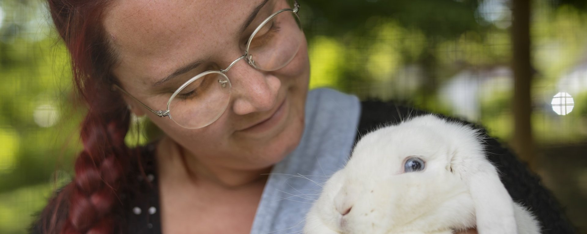 Rothaarige Frau schmust mit einem weißen Kaninchen.