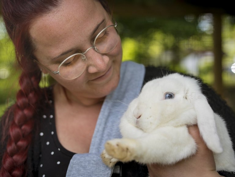 Rothaarige Frau schmust mit einem weißen Kaninchen.
