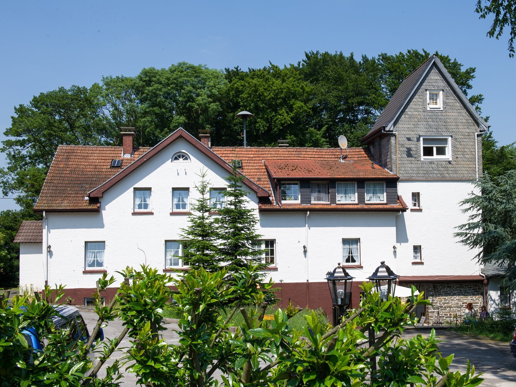 Aussenansicht: Gut Sassenscheid - im Vordergrund grüne Sträucher und Bäume