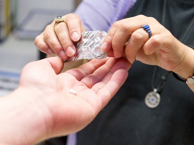 Symbolbild: Tabletten werden in eine ausgestreckte Hand gegeben