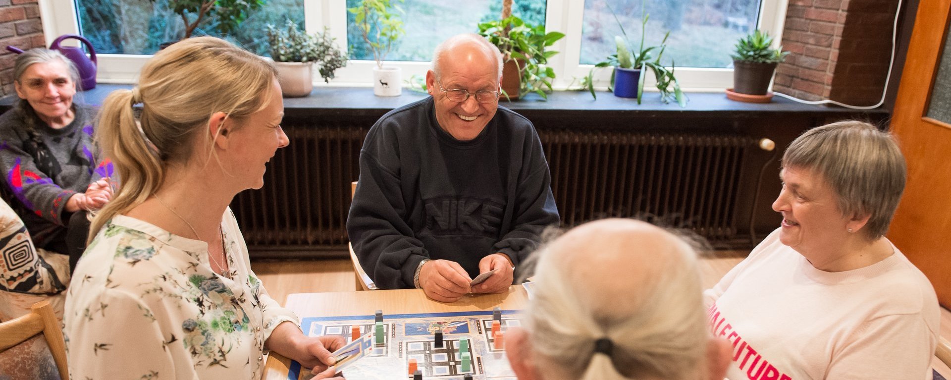 Männer und Frauen spielen ein Brettspiel und lachen dabei