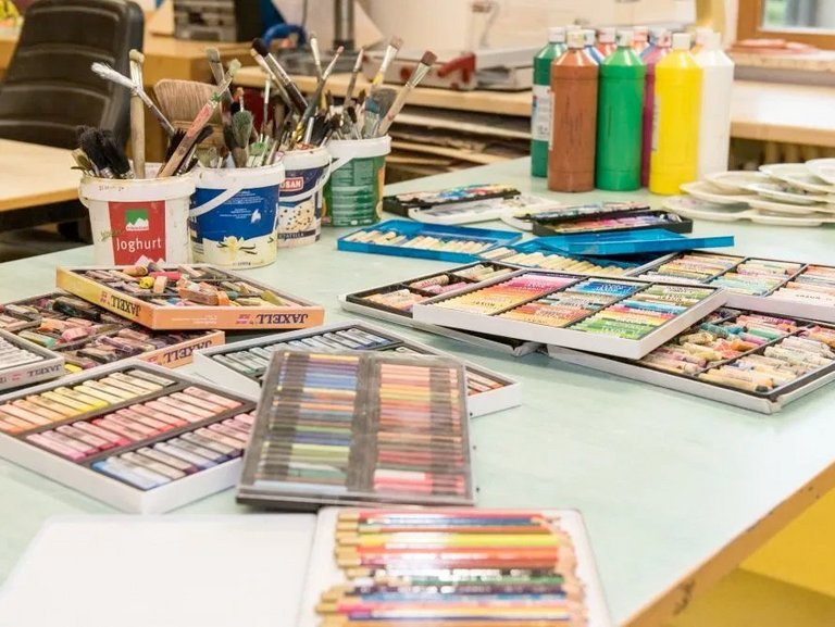 in der Werkstatt: auf einem Tisch liegen Stifte, Farben und Pinsel